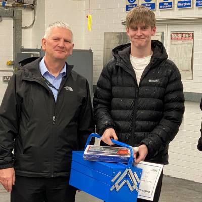 A student with members of staff after being presented with their engineering toolkit