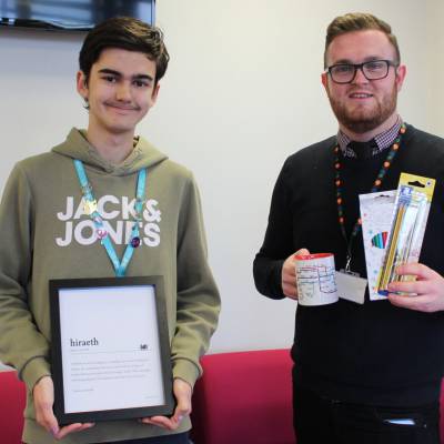 Tom Roberts being presented with his prize by Grŵp Llandrillo Menai Welsh Language Facilitator Samuel Stones