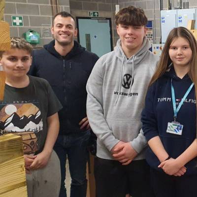 Thomos Evans, Luke Owen Hughes and Scarlet Lewis with practical skills supervisor Tom Coulthard in the carpentry workshop at Coleg Menai