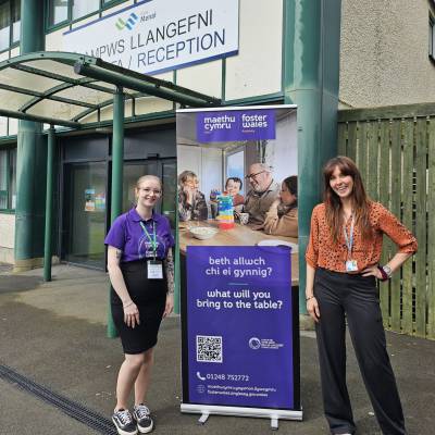 Staff Wellbeing Coordinator Jenny Davies with a member of Foster Wales staff outside Coleg Menai reception in Llangefni