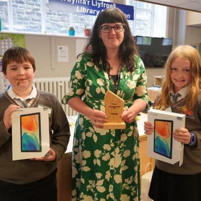 Cynan and Erin with tablets after winning Coleg Meirion-Dwyfor’s coding competition, with assistant principal Fflur Jones holding the trophy