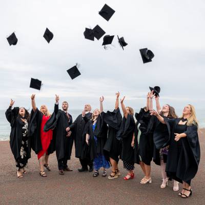 Myfyrwyr yn dathlu graddio ar y promenâd yn Llandudno