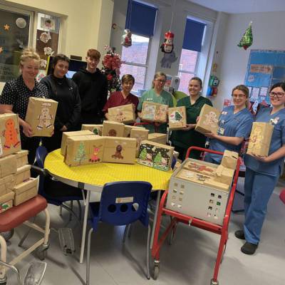 Students Courtney Riches and Cameron Newman with Wrexham Maelor hospital staff and gift boxes they created for children at the hospital