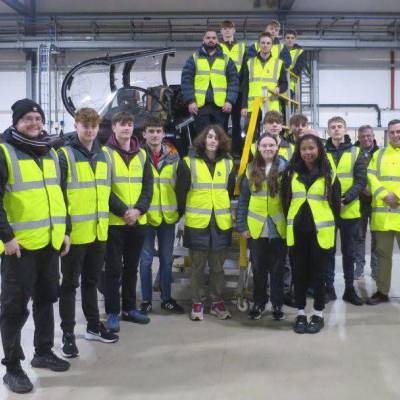 Coleg Menai students and staff next to a Hawk T2 aircraft in a hangar at Babcock International, RAF Valley