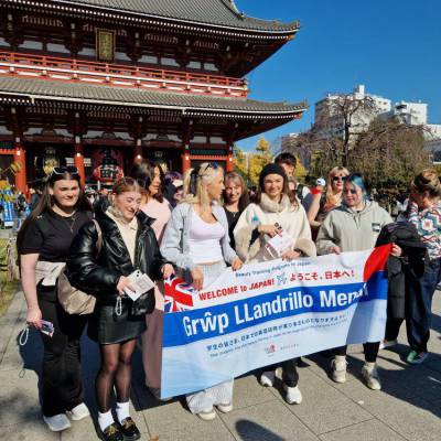 Myfyrwyr o Goleg Menai ger Sensoji Temple, Tokyo gyda baner yn dweud 'Croeso i Japan, Grŵp Llandrillo Menai'