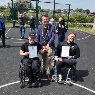 Former Coleg Menai students Ryan and Kieran Jones on the new basketball court at Parc Mwd with Councillor Neil Tuck