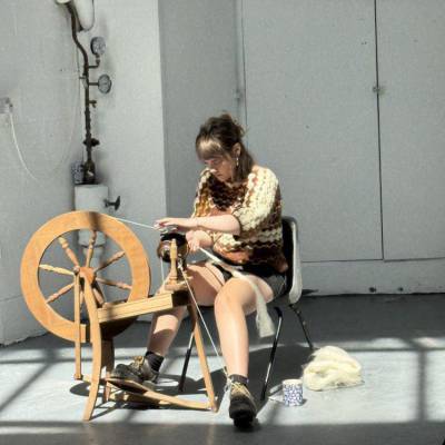 Cadi Richardson spinning yarn on a spinning wheel in the Art Foundation studio at Coleg Menai